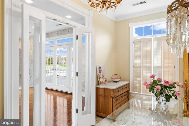 foyer featuring light hardwood / wood-style floors, french doors, ornamental molding, and plenty of natural light