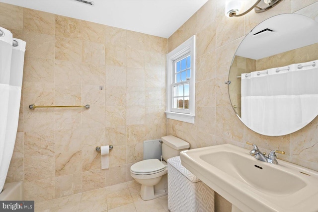 full bathroom featuring sink, toilet, tile patterned floors, tile walls, and shower / tub combo with curtain