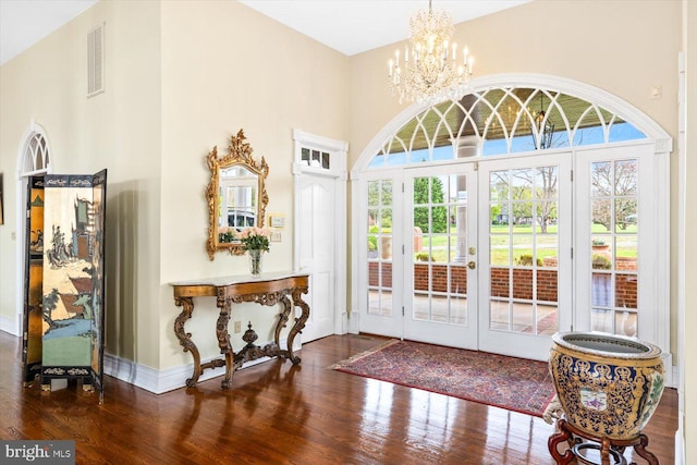 doorway featuring an inviting chandelier, french doors, dark wood-type flooring, and a towering ceiling