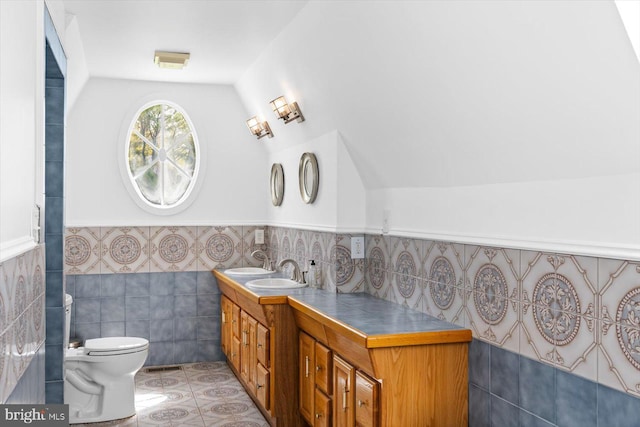 bathroom featuring tile walls, vaulted ceiling, toilet, vanity, and tile patterned floors