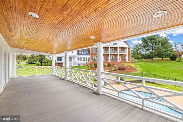 wooden deck with a swimming pool and a lawn