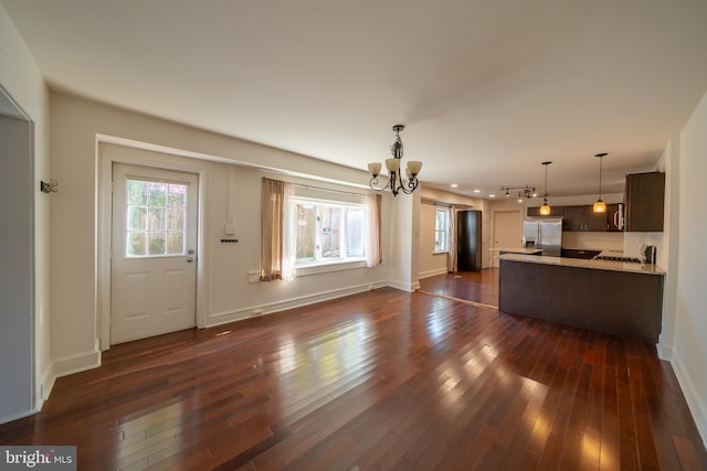 unfurnished living room featuring dark hardwood / wood-style flooring and an inviting chandelier