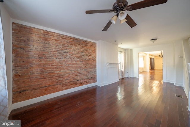 interior space with ceiling fan, dark wood-type flooring, and brick wall