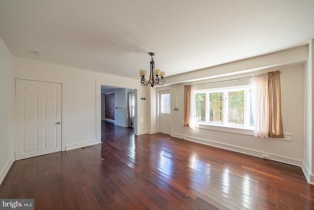 empty room with a chandelier and dark wood-type flooring