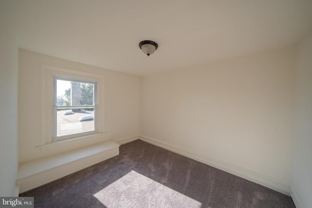 spare room featuring dark colored carpet