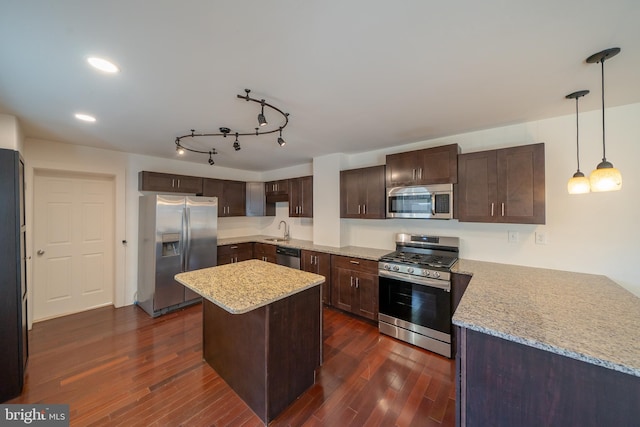 kitchen featuring sink, hanging light fixtures, appliances with stainless steel finishes, dark hardwood / wood-style flooring, and light stone counters