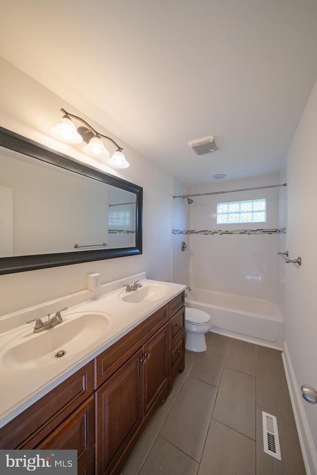 full bathroom with tile patterned flooring, vanity, tiled shower / bath combo, and toilet