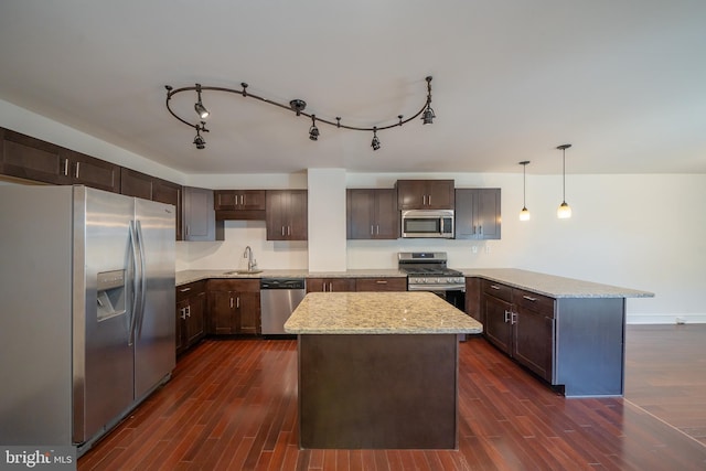 kitchen featuring a kitchen island, dark wood-type flooring, decorative light fixtures, and appliances with stainless steel finishes