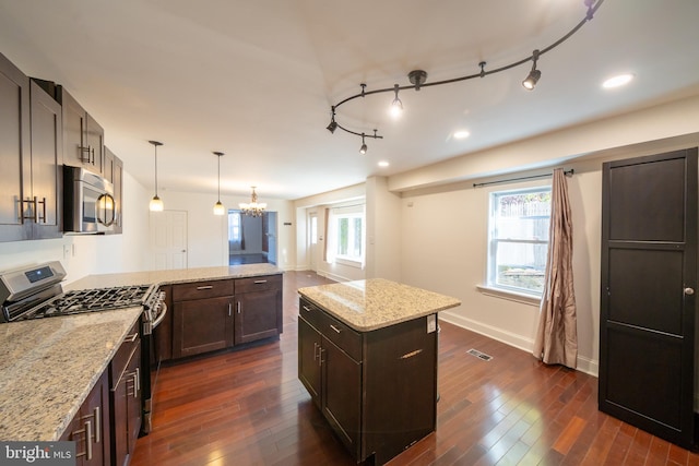 kitchen featuring light stone countertops, appliances with stainless steel finishes, decorative light fixtures, a chandelier, and dark hardwood / wood-style floors