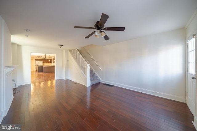 unfurnished living room featuring ceiling fan with notable chandelier and dark wood-type flooring