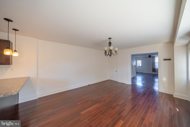 unfurnished dining area with ceiling fan with notable chandelier and dark hardwood / wood-style floors