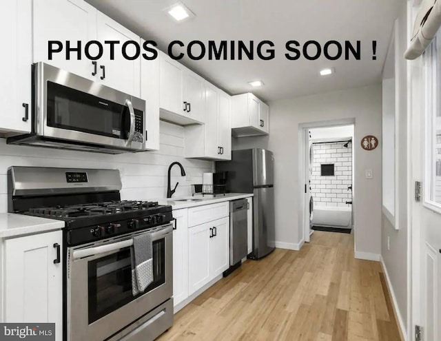 kitchen featuring white cabinetry, stainless steel appliances, light hardwood / wood-style floors, and tasteful backsplash