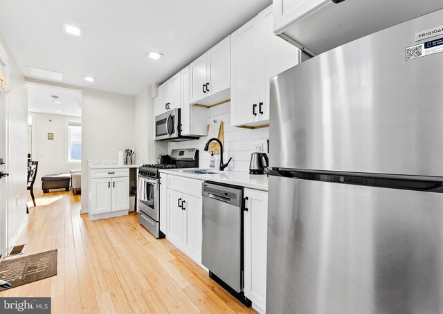 kitchen with white cabinetry, light wood-type flooring, appliances with stainless steel finishes, and sink