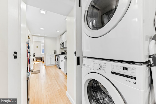 laundry area featuring stacked washer and clothes dryer and light wood-type flooring