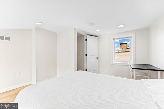 bedroom with vaulted ceiling and hardwood / wood-style flooring