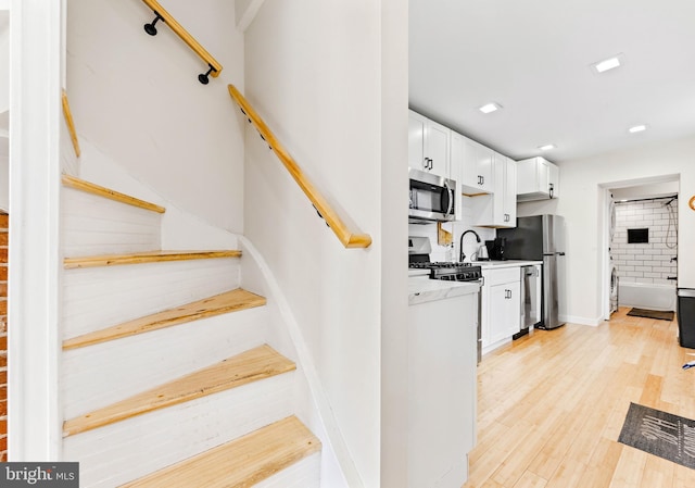 stairs featuring sink and hardwood / wood-style floors