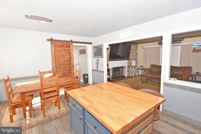 kitchen featuring dark hardwood / wood-style floors, ceiling fan, a fireplace, blue cabinetry, and a barn door