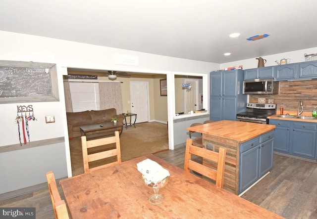 kitchen featuring dark hardwood / wood-style flooring, decorative backsplash, sink, blue cabinetry, and appliances with stainless steel finishes