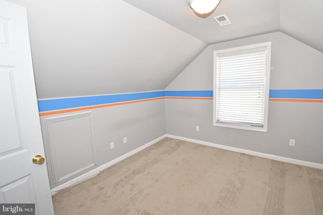 bonus room with lofted ceiling and light carpet