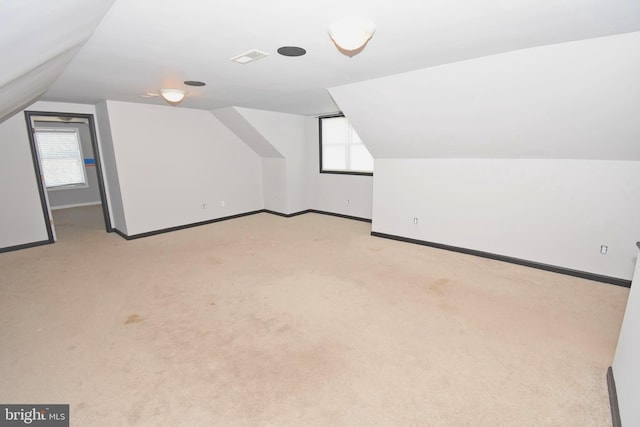 additional living space with vaulted ceiling, light colored carpet, and a healthy amount of sunlight