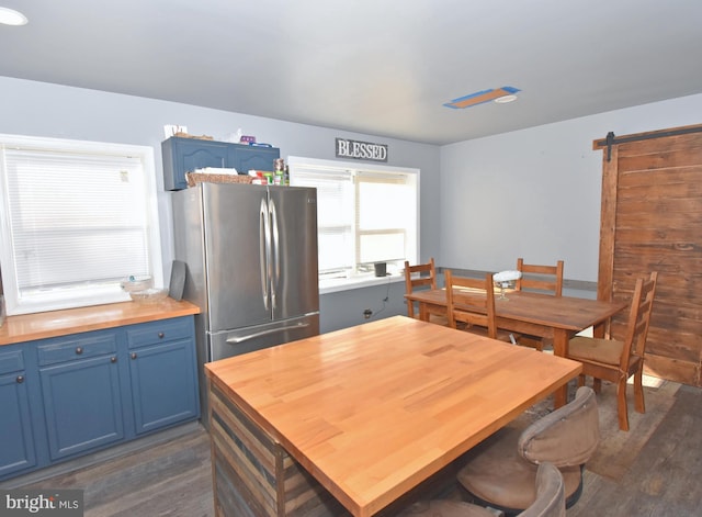 dining area with dark wood-type flooring and a barn door