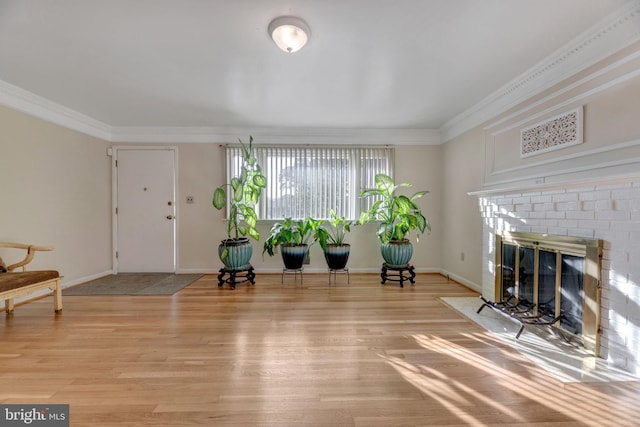 living room with crown molding, hardwood / wood-style flooring, and a brick fireplace