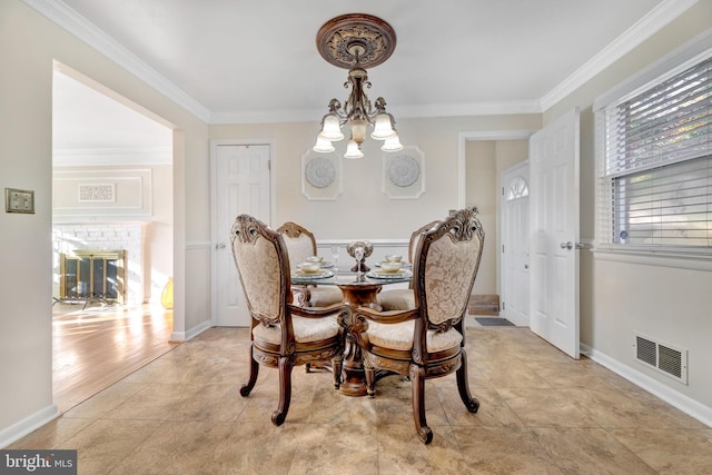 dining space with light wood-type flooring, crown molding, a fireplace, and an inviting chandelier