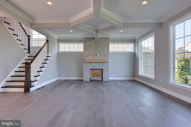 unfurnished living room featuring plenty of natural light, ornamental molding, wood finished floors, and a tile fireplace