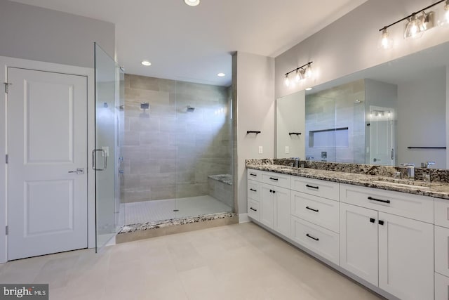 bathroom with double vanity, a shower stall, and a sink