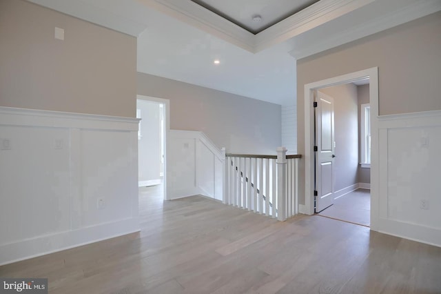 hallway featuring wainscoting, a decorative wall, wood finished floors, and an upstairs landing