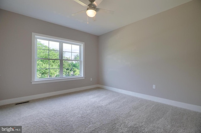 carpeted empty room with a ceiling fan, visible vents, and baseboards