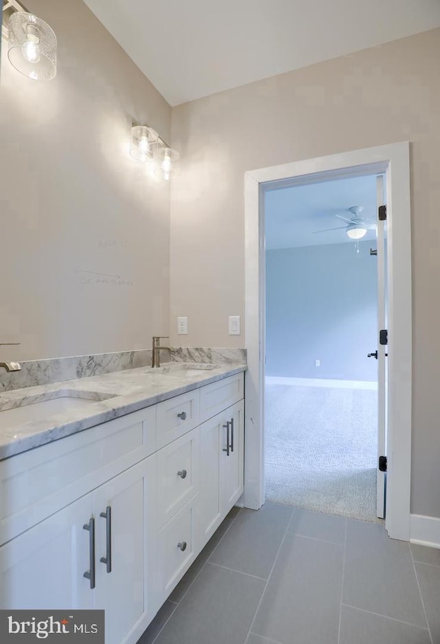 bathroom featuring double vanity, tile patterned flooring, baseboards, and a sink