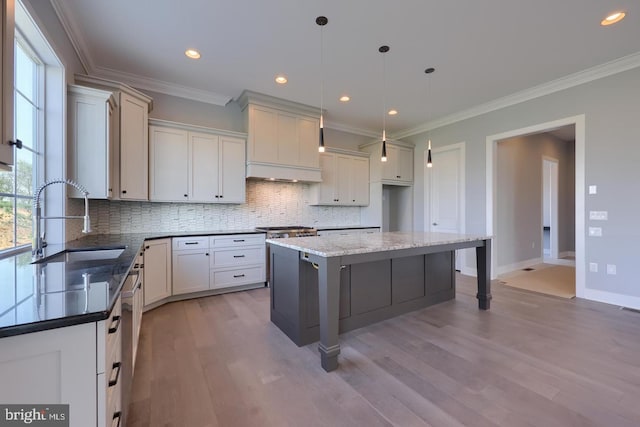 kitchen featuring ornamental molding, tasteful backsplash, a sink, and light wood-style floors