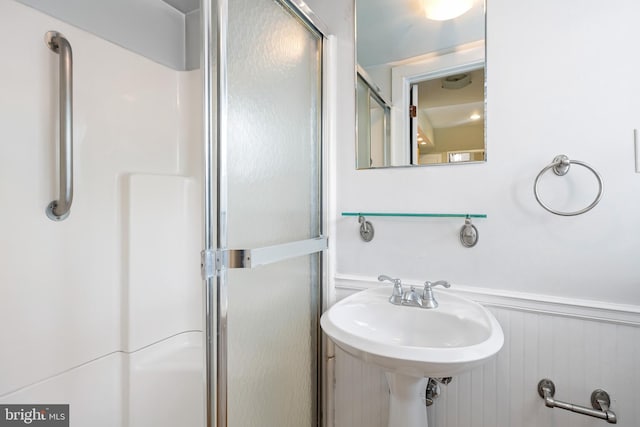 bathroom featuring a shower with door and sink