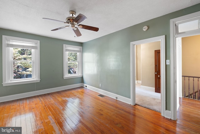 empty room featuring a textured ceiling, light hardwood / wood-style floors, and ceiling fan