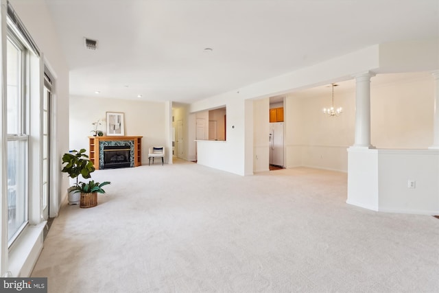 carpeted living room with ornate columns and an inviting chandelier