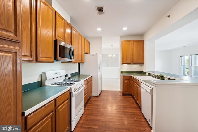 kitchen featuring kitchen peninsula, an inviting chandelier, dark hardwood / wood-style floors, sink, and white appliances