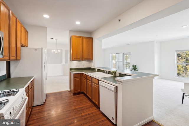 kitchen with white appliances, a wealth of natural light, kitchen peninsula, and dark hardwood / wood-style flooring