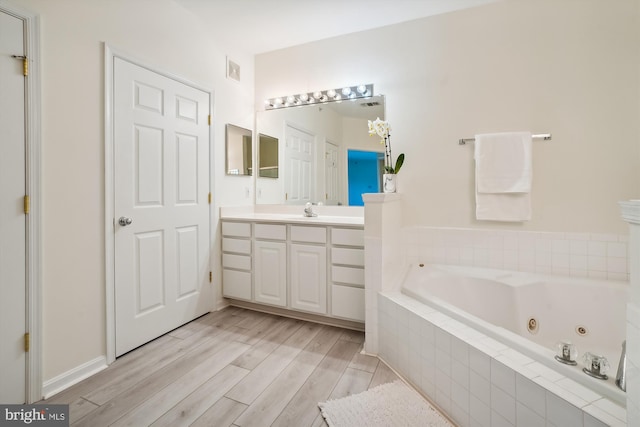 bathroom with vanity, wood-type flooring, and tiled bath