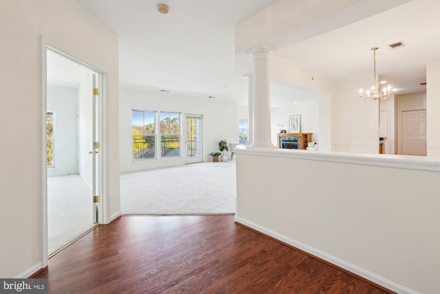 corridor with an inviting chandelier, hardwood / wood-style floors, and decorative columns