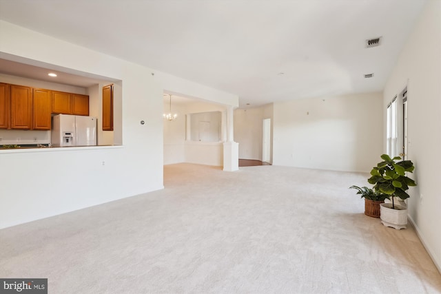 living room with light carpet, decorative columns, and an inviting chandelier