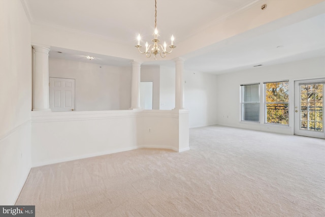 carpeted spare room with ornamental molding, a chandelier, and decorative columns