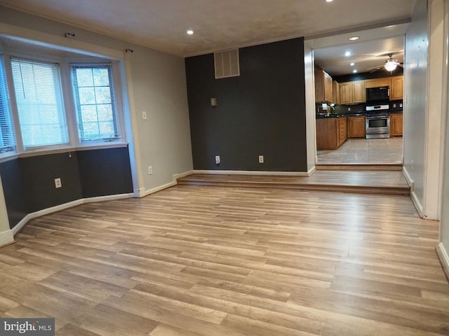 unfurnished living room with light wood-type flooring and ceiling fan