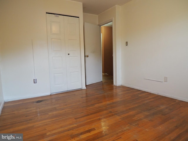 unfurnished bedroom with dark wood-type flooring and a closet