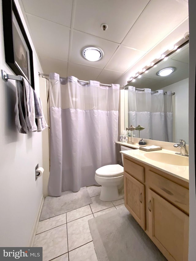 bathroom with a paneled ceiling, tile patterned flooring, vanity, a shower with curtain, and toilet