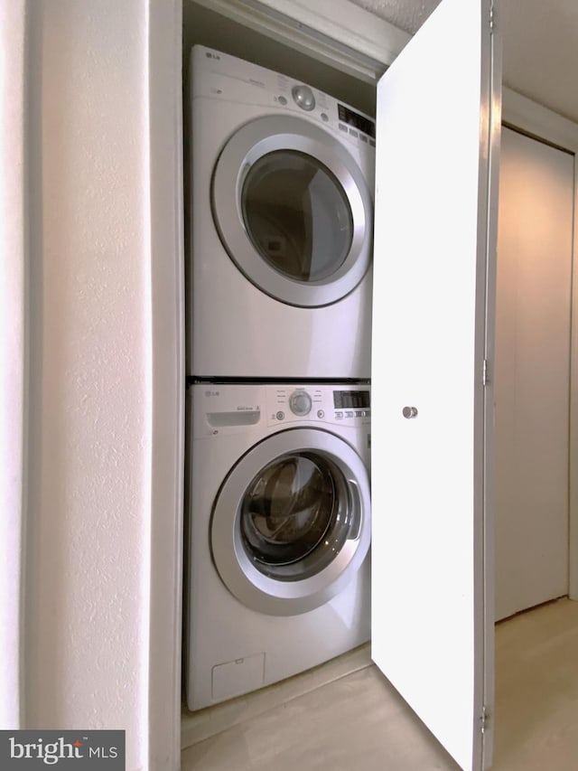 clothes washing area with stacked washer and clothes dryer