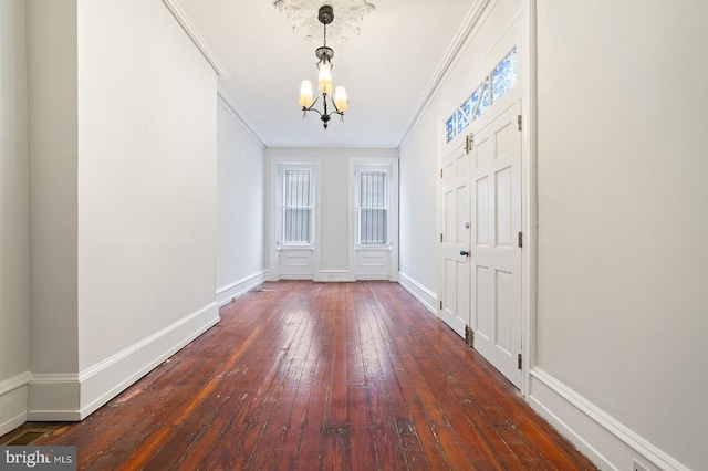 foyer entrance with crown molding, a notable chandelier, and dark hardwood / wood-style flooring