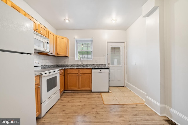 kitchen featuring decorative backsplash, sink, light wood-type flooring, and white appliances