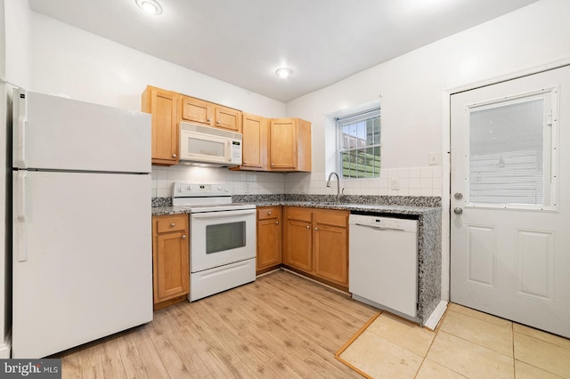 kitchen featuring white appliances, decorative backsplash, sink, and light wood-type flooring