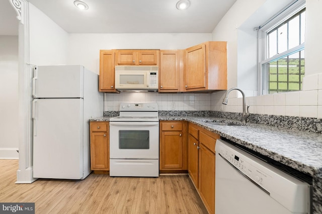 kitchen with sink, light stone countertops, light wood-type flooring, white appliances, and tasteful backsplash